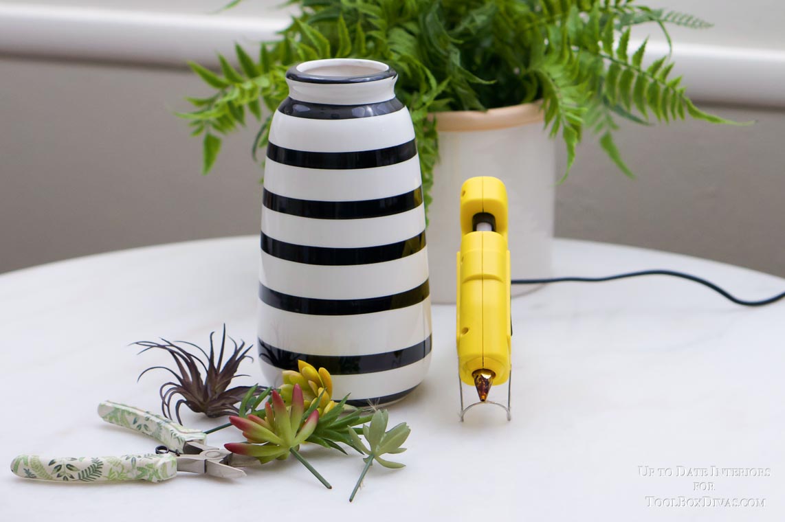 white and black striped vase with yellow hot glue gun, plant, and succulents